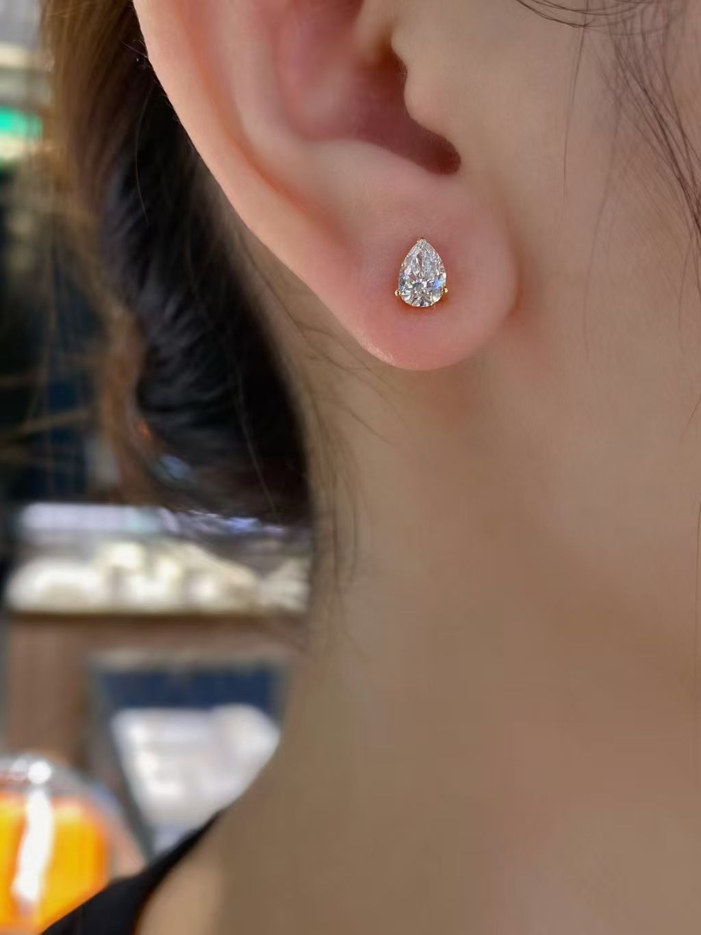 Pear solitaire lab diamond stud earrings worn on ear