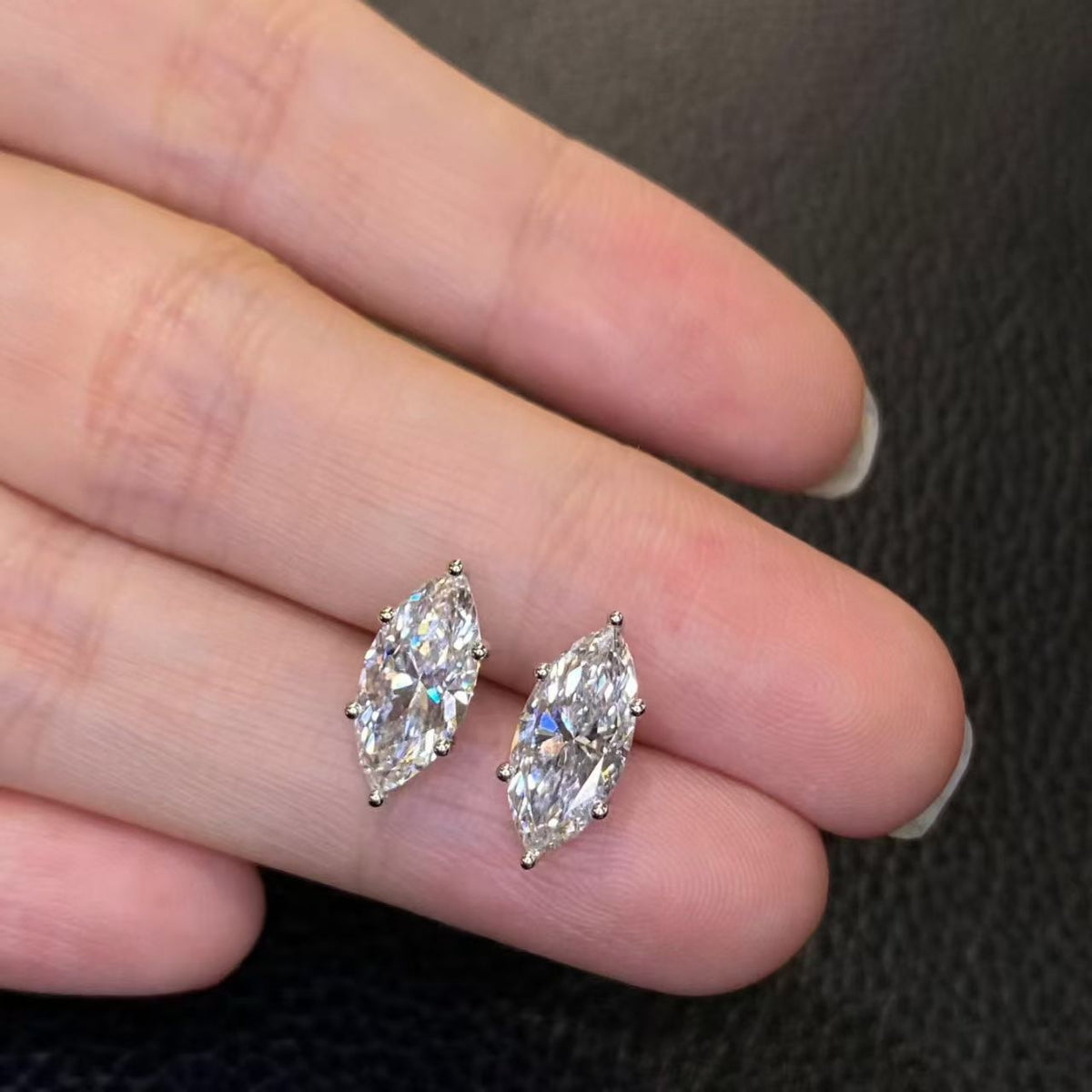Marquise solitaire lab diamond stud earrings held on fingertip - top view